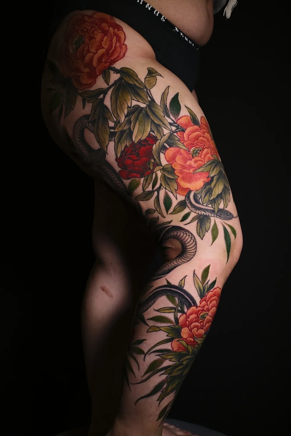 Large-scale Japanese leg tattoo, red peonies, by Levi Taylor at NEST Studio, Melbourne
